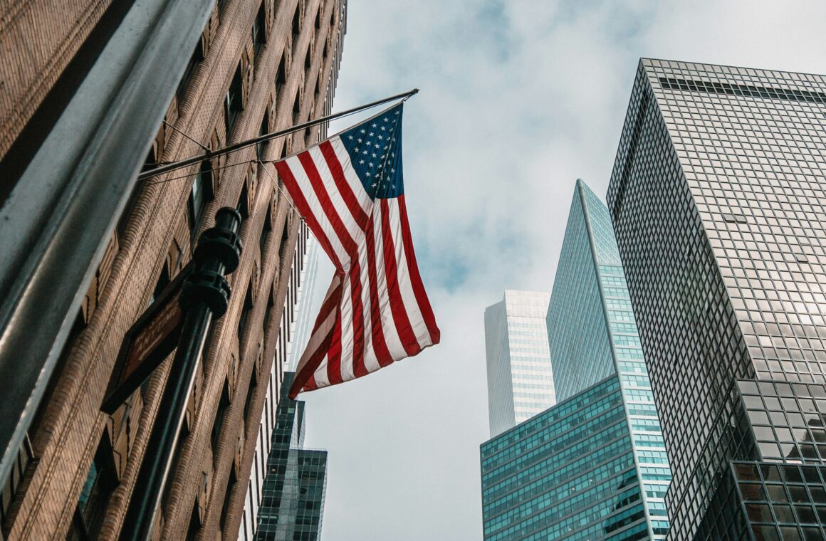 US flag flying in front of tall US skyscrapers